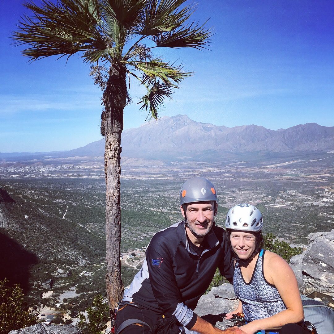 A man and a woman are posing for a picture on top of a mountain
