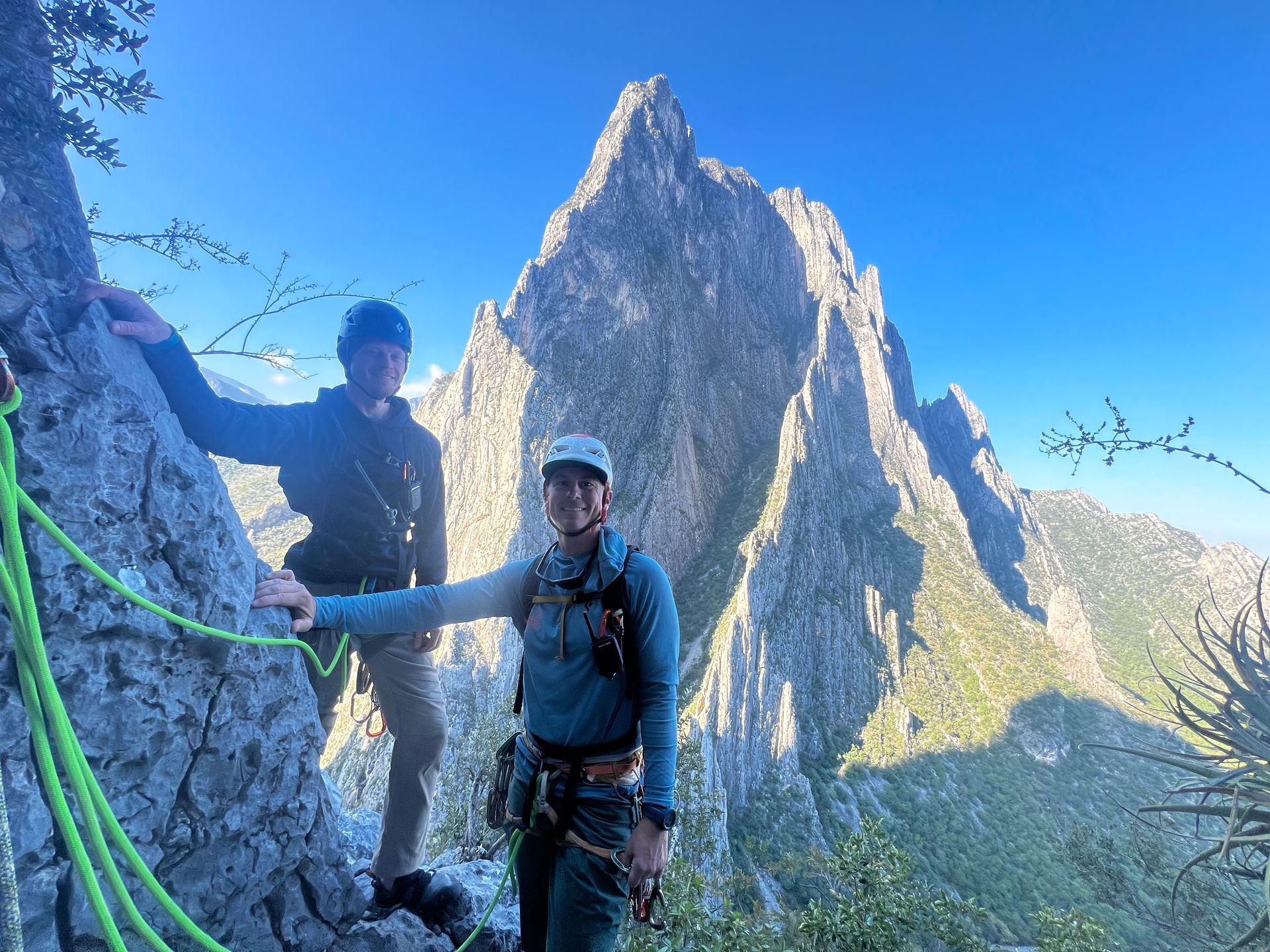 Two men are standing next to each other on top of a mountain.