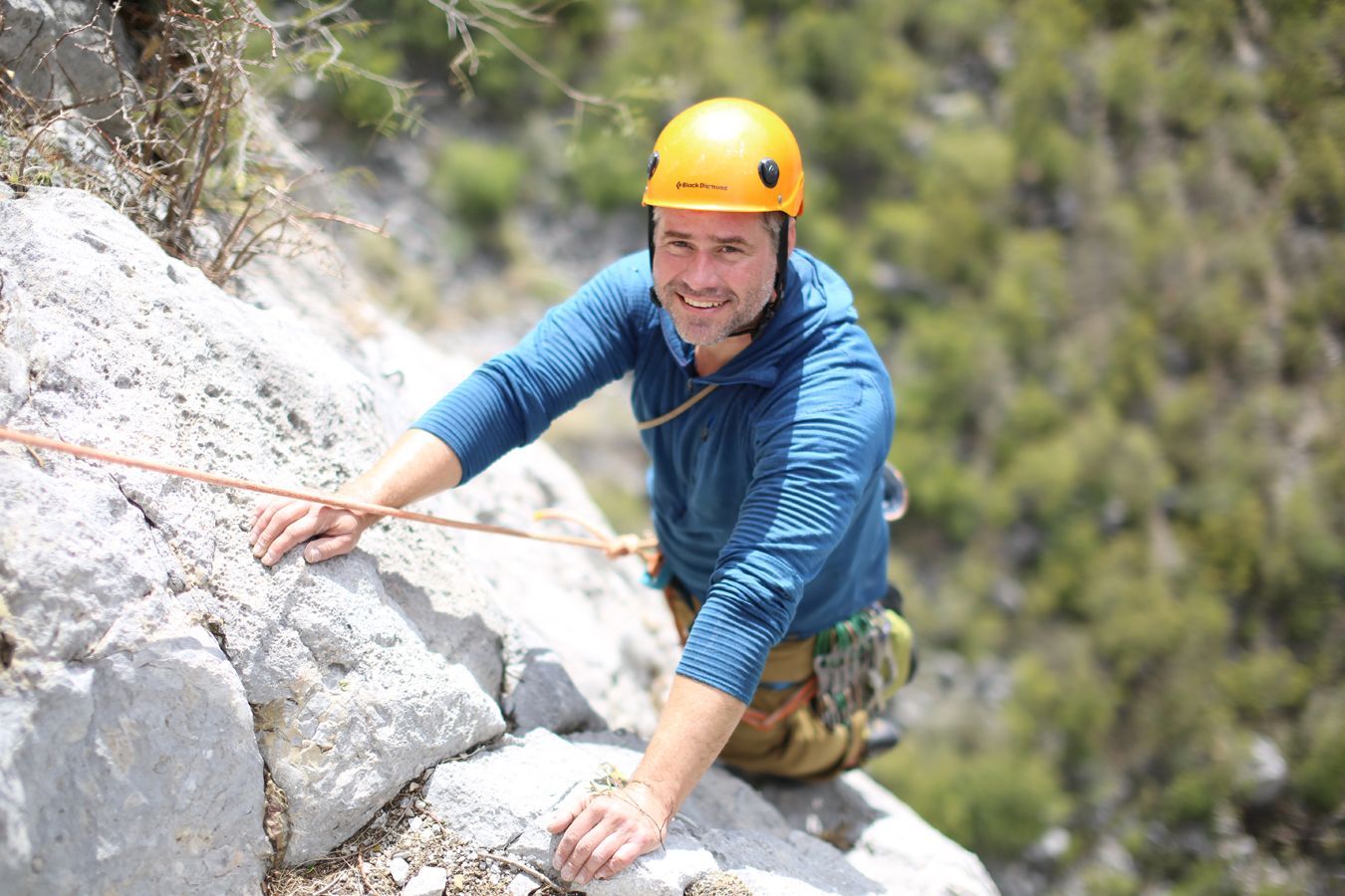 A man wearing a helmet is climbing a rock wall.