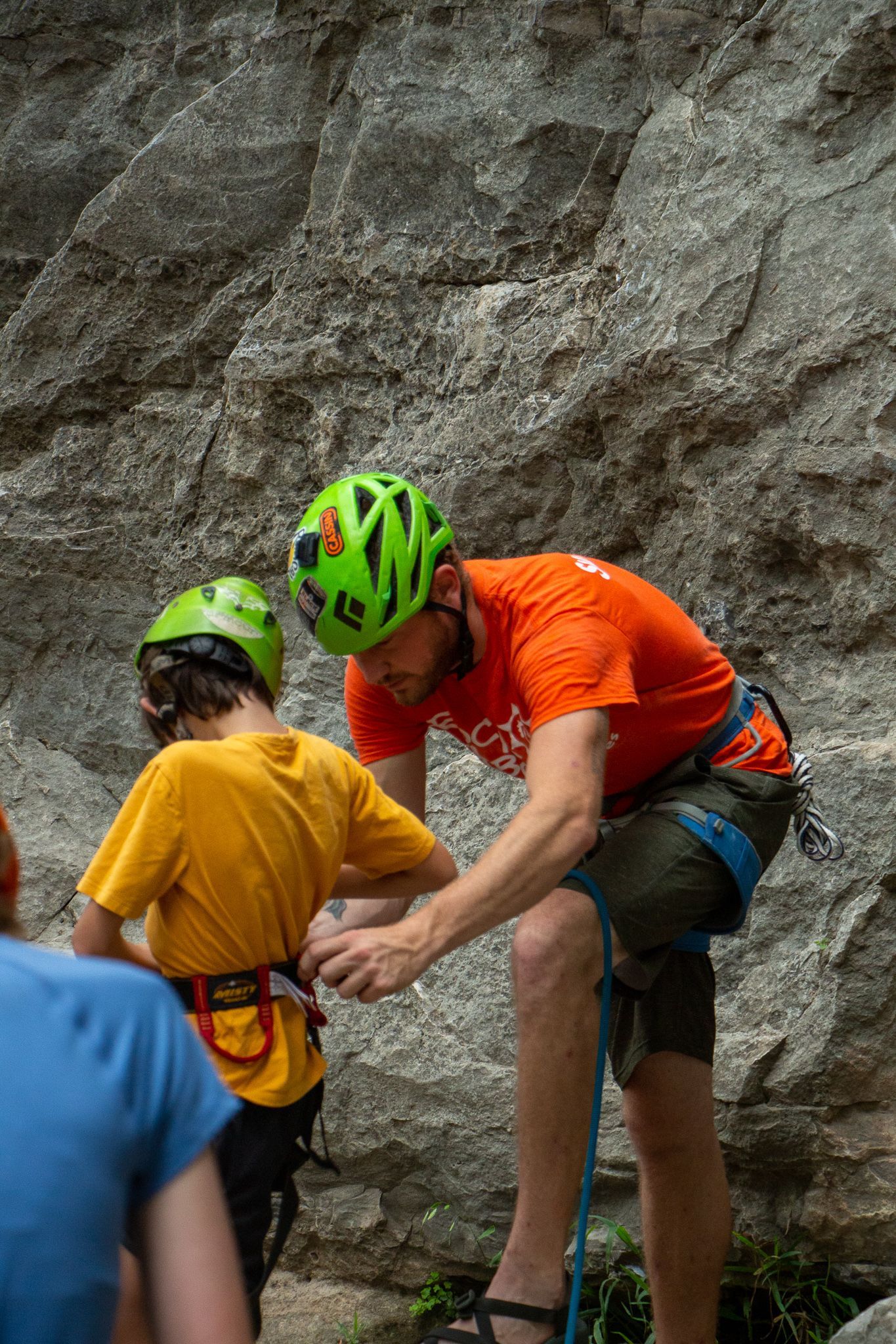 A man is helping a young boy climb a rock wall.