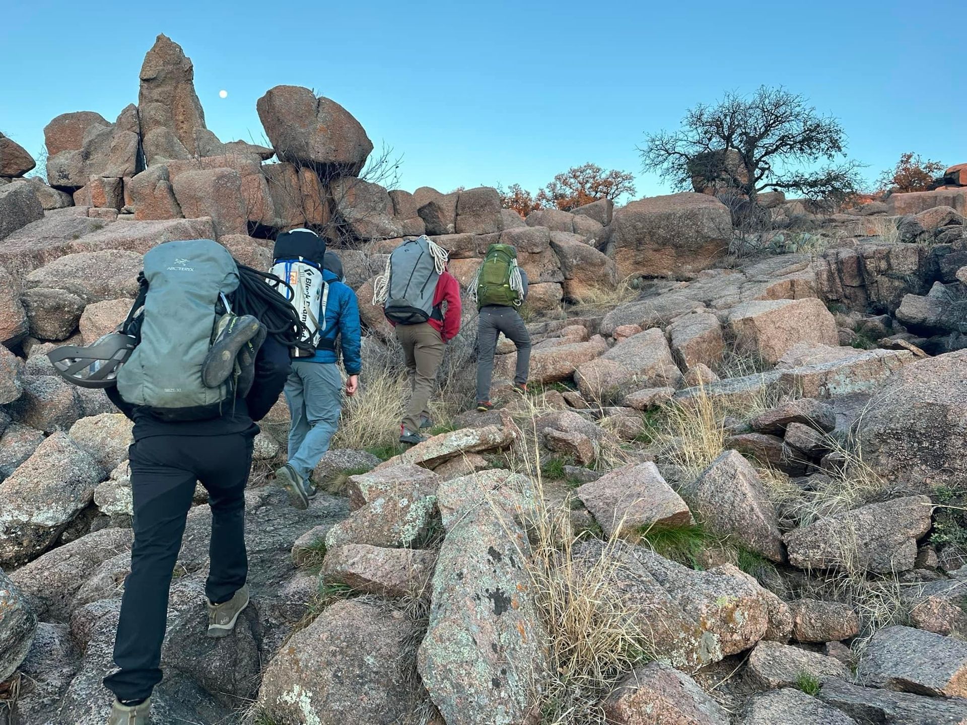 A group hiking with packs through granite boulder terrain at Enchanted Rock, Texas