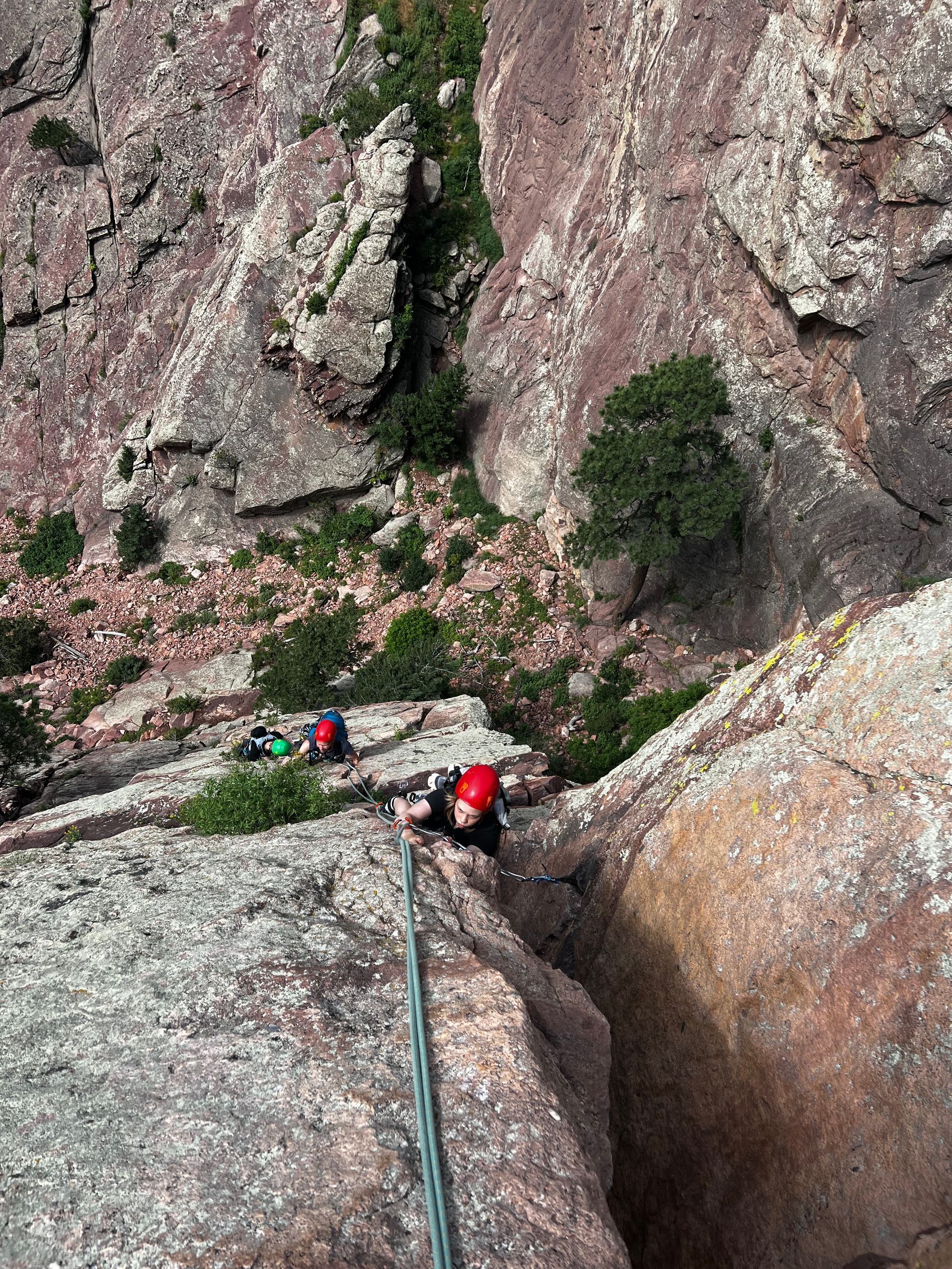 A person is climbing up a rock wall with a rope.