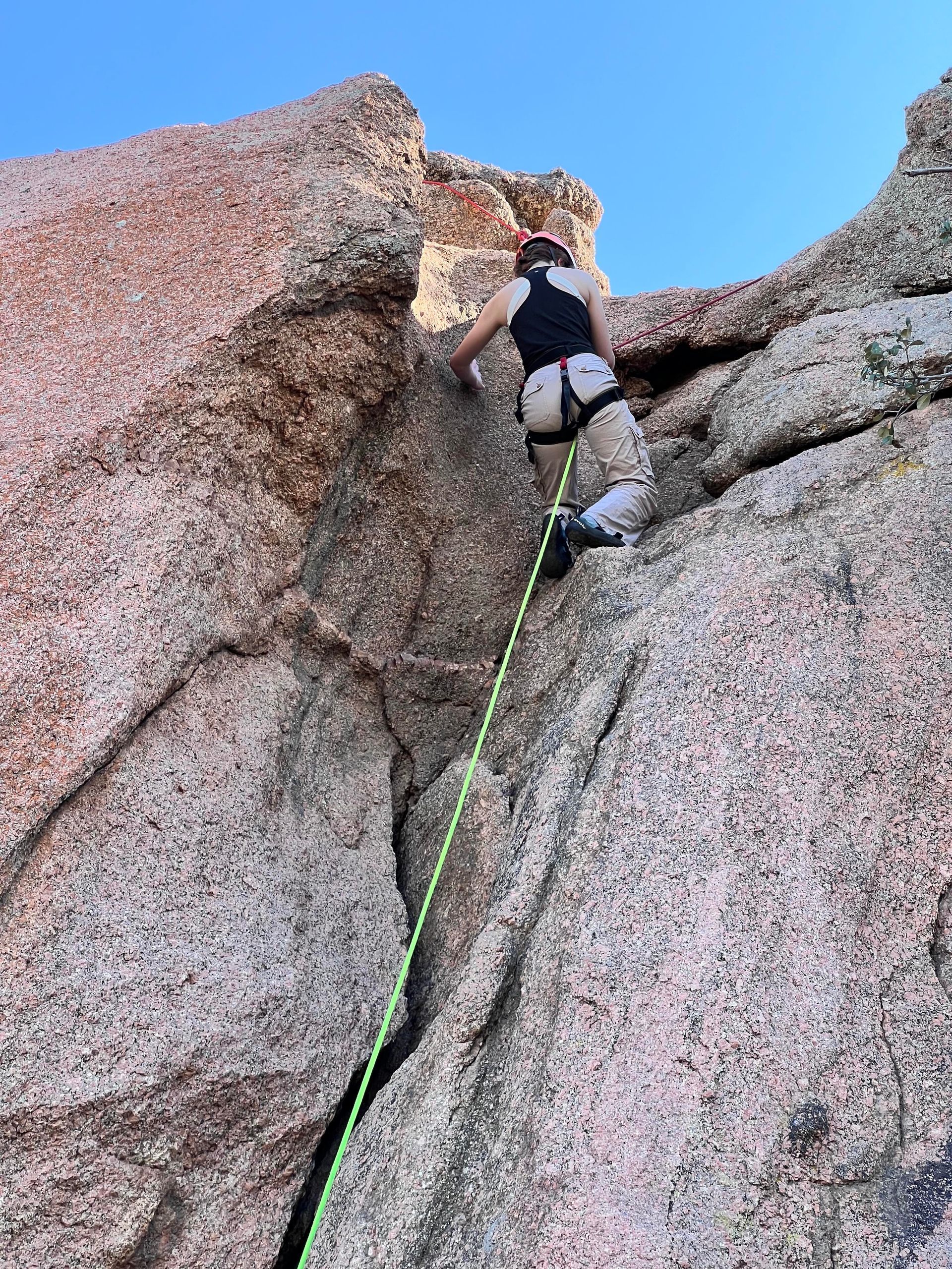 A person is climbing up a rock with a green rope