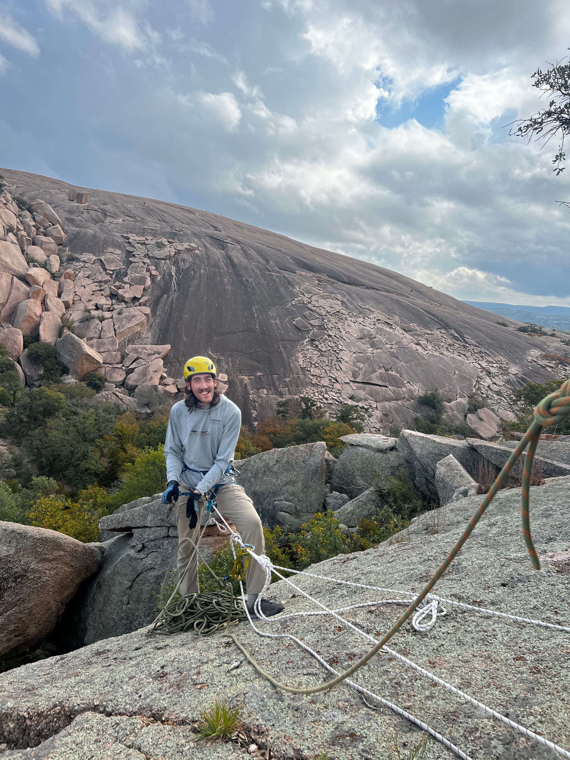 A man in a helmet is standing on top of a rocky mountain.