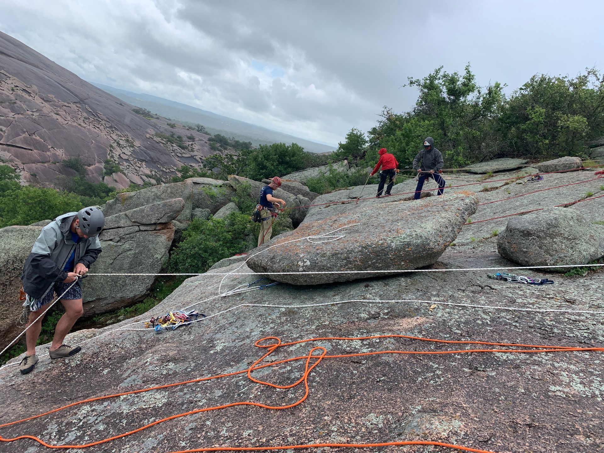A child wearing an orange helmet climbs a rock