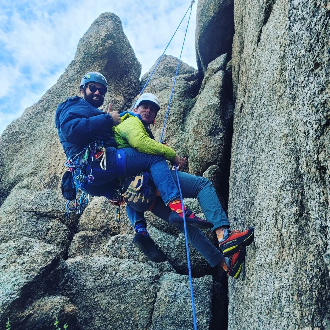 A man and a woman are climbing up a rock wall.