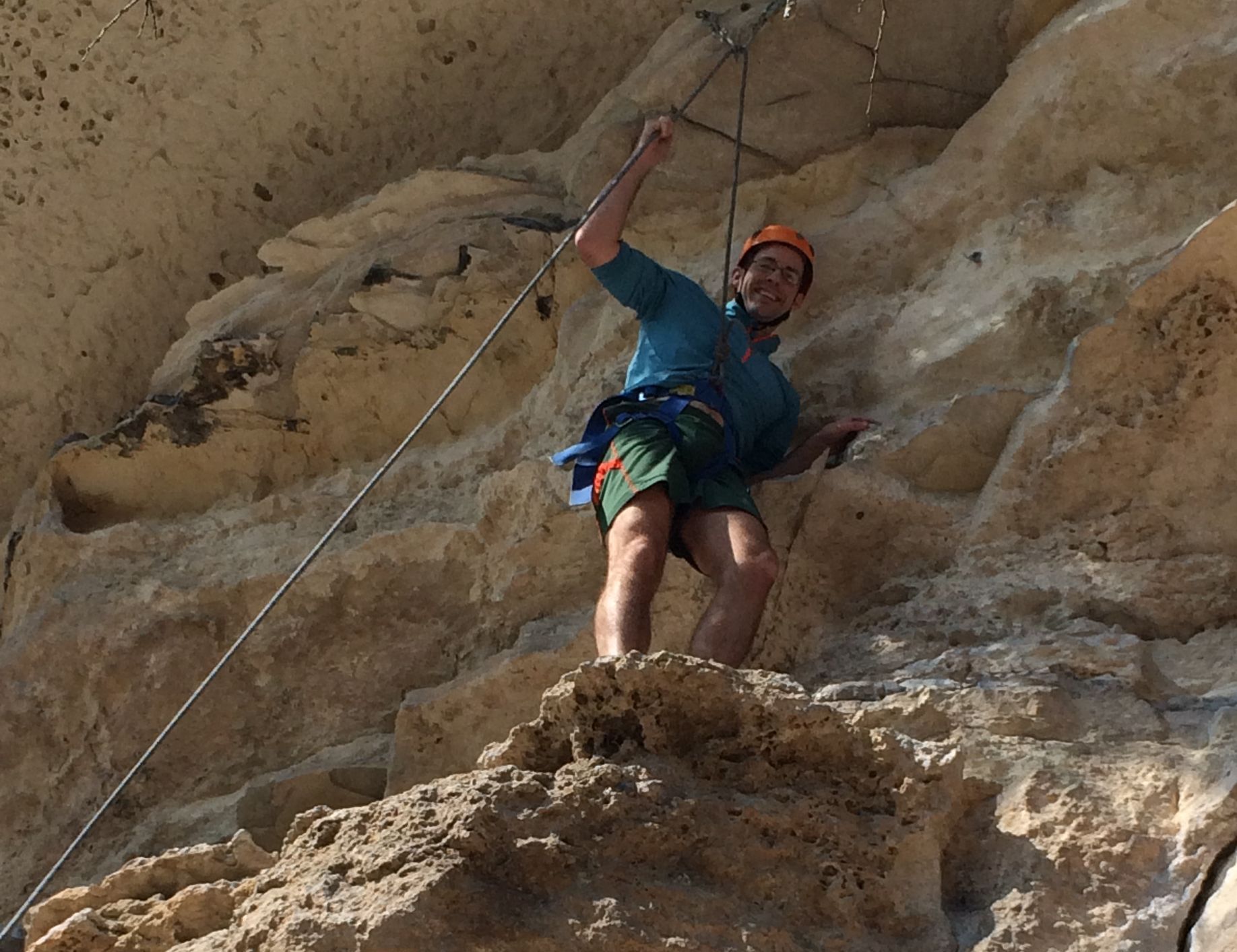 A man is climbing a rock wall with a rope