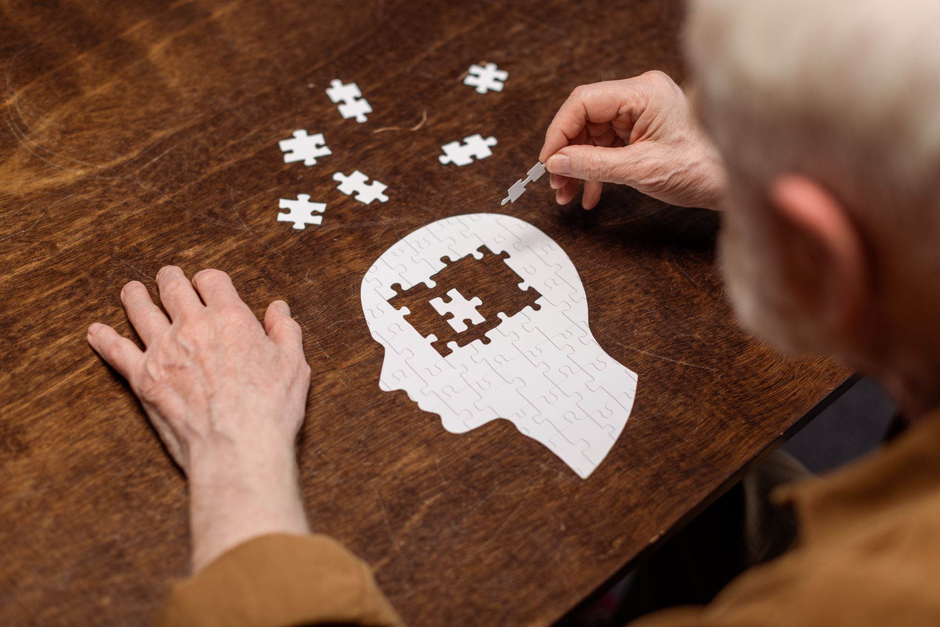 Mann baut Puzzle zum Thema Demenz