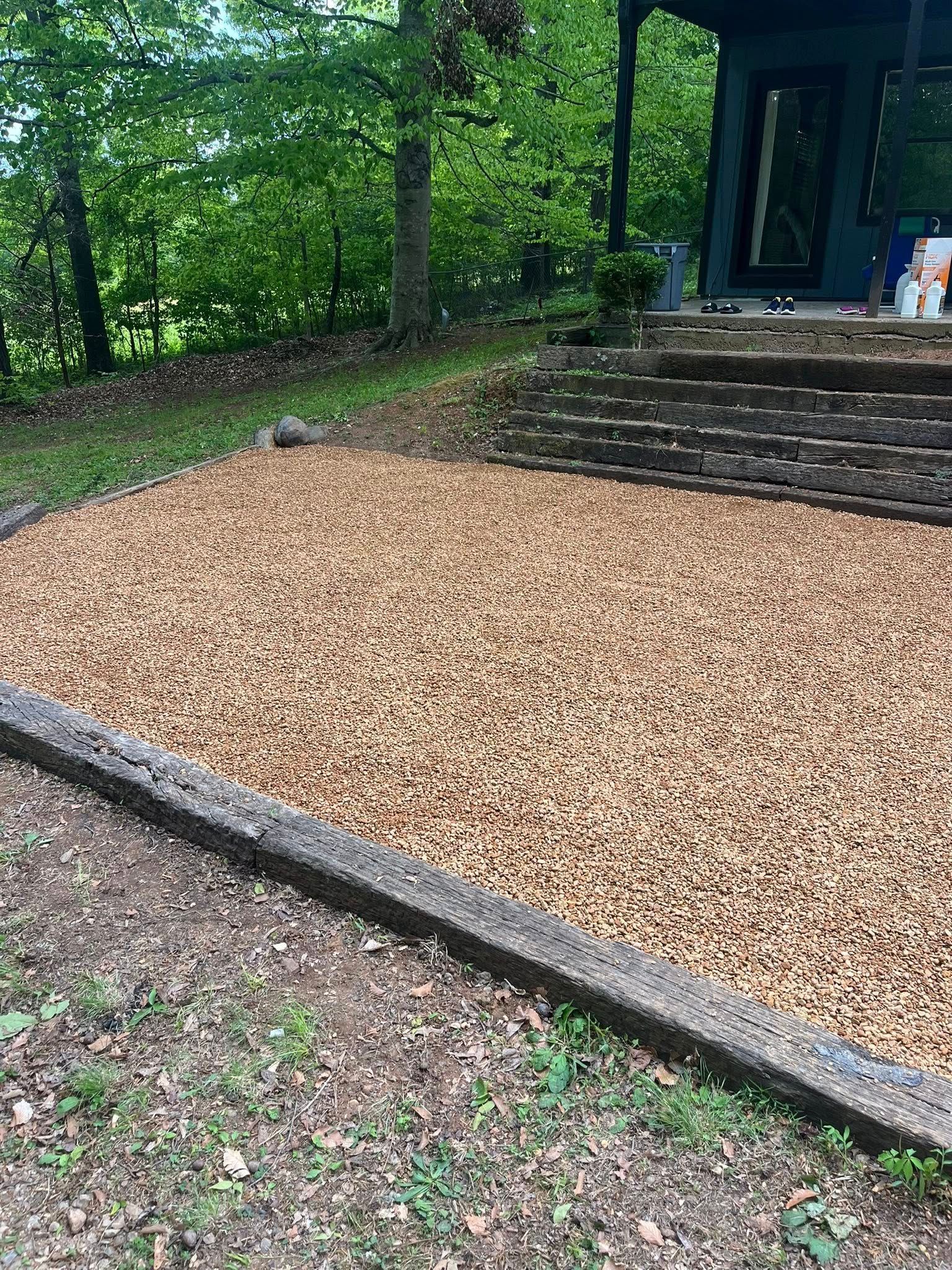 Gravel-covered garden bed bordered by timber, beside stone steps and a house porch