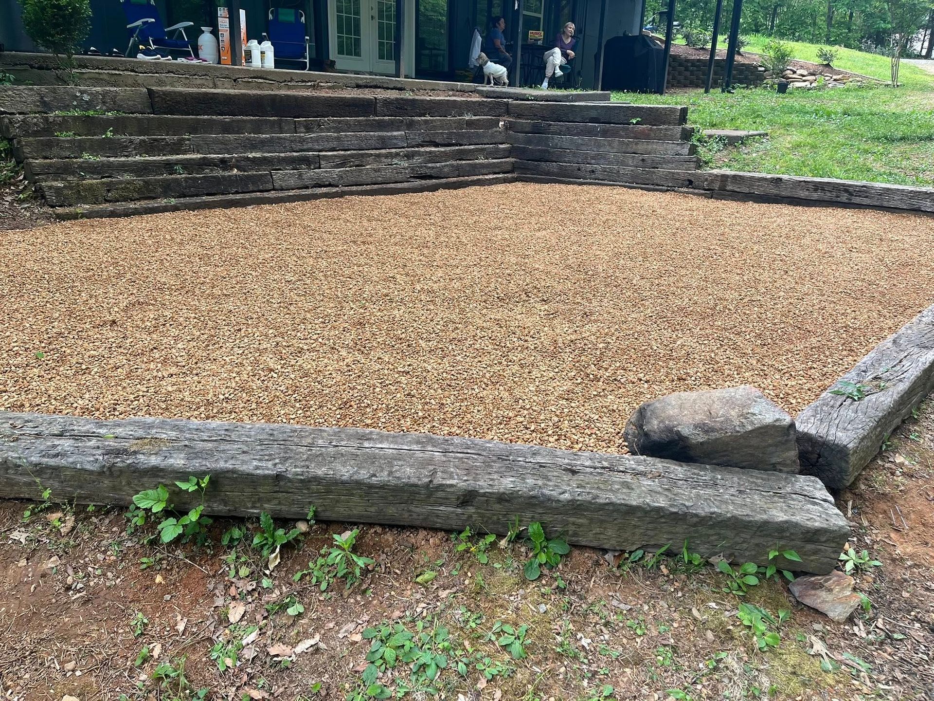 Stone-edged gravel area in a park, with steps and greenery in the background.