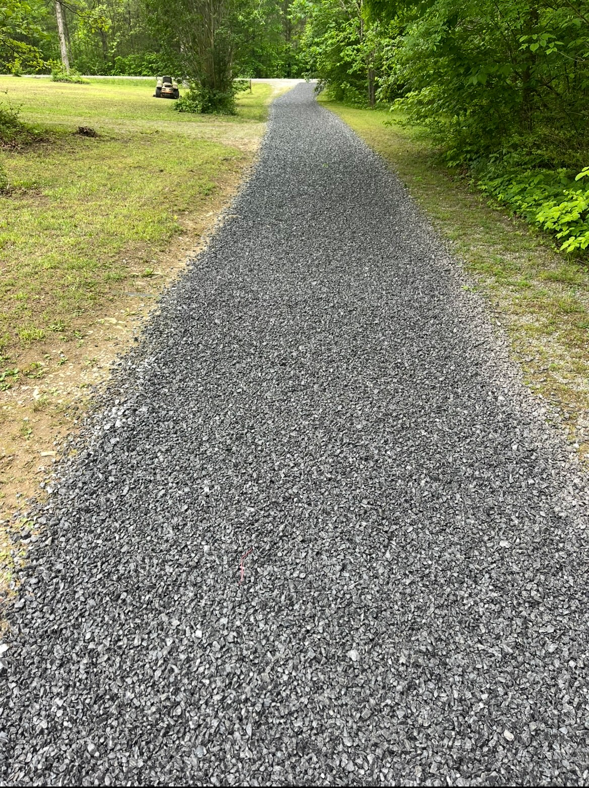 Gravel path through a green wooded area, stretching into the distance