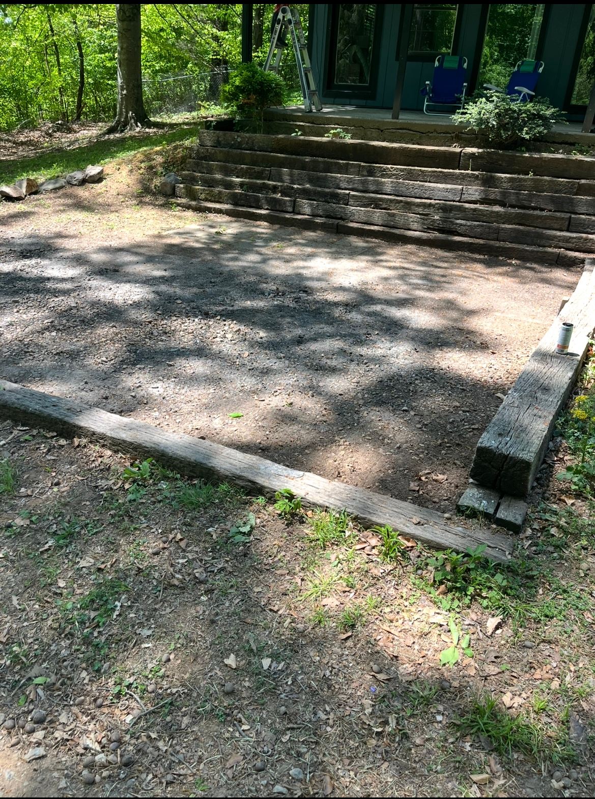 Concrete steps and a paved platform in a shaded park clearing with trees and grass nearby