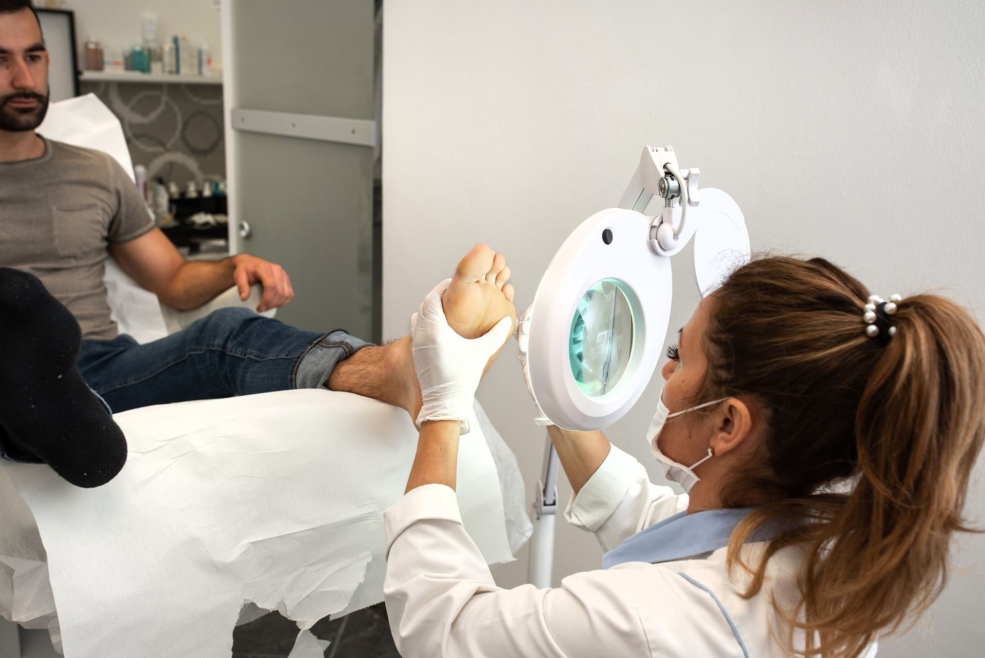 A woman is examining a man 's foot with a magnifying glass.