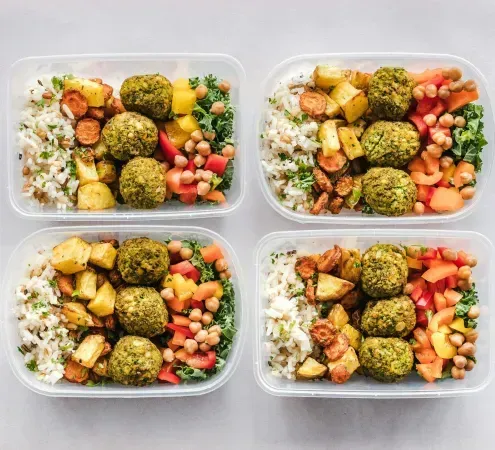 Four plastic containers filled with different types of food on a table.