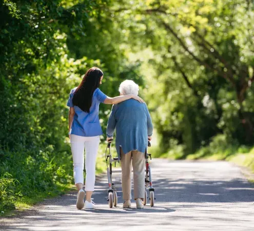 A woman is helping an elderly woman with a walker.