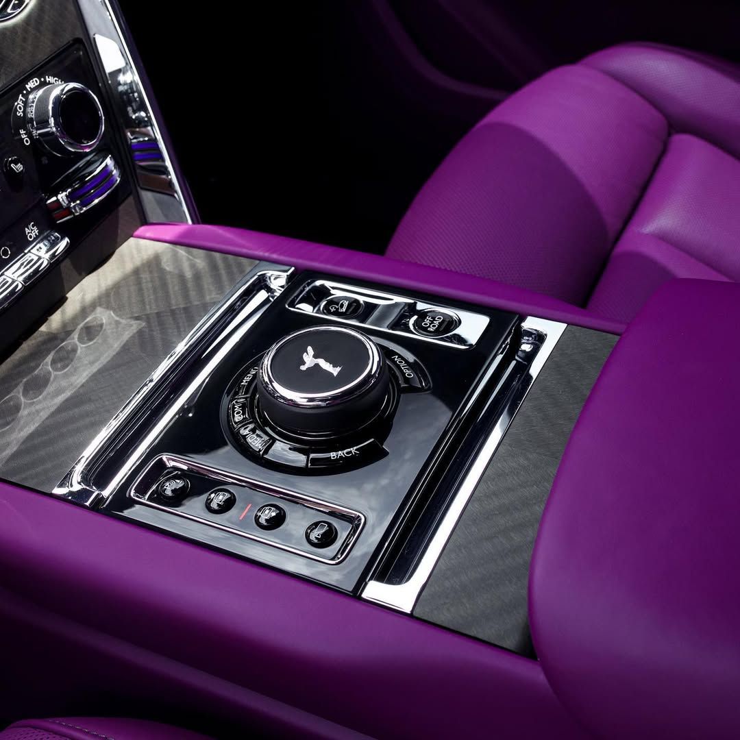 Luxury car interior with vibrant purple leather upholstery and a carbon fiber center console featuring a rotary dial.