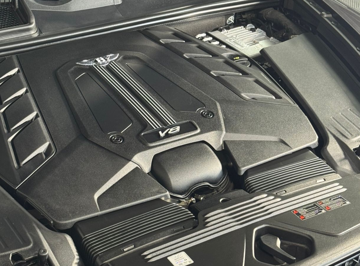 Close-up of a modern Bentley V8 car engine under a black plastic cover.