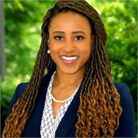 A woman with dreadlocks is wearing a blue jacket and a white shirt.