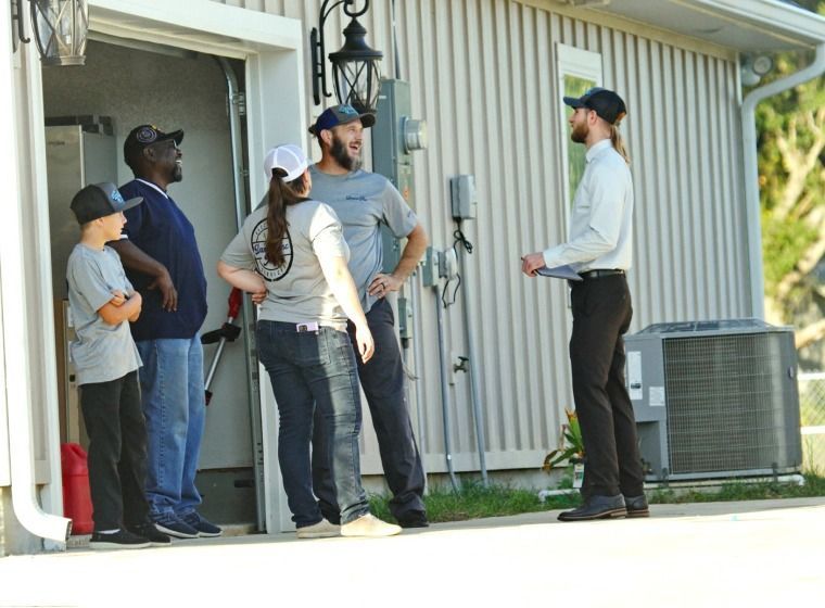 A group of people are standing outside of a house talking to a man - Milton, FL - Damn Fine Jobs