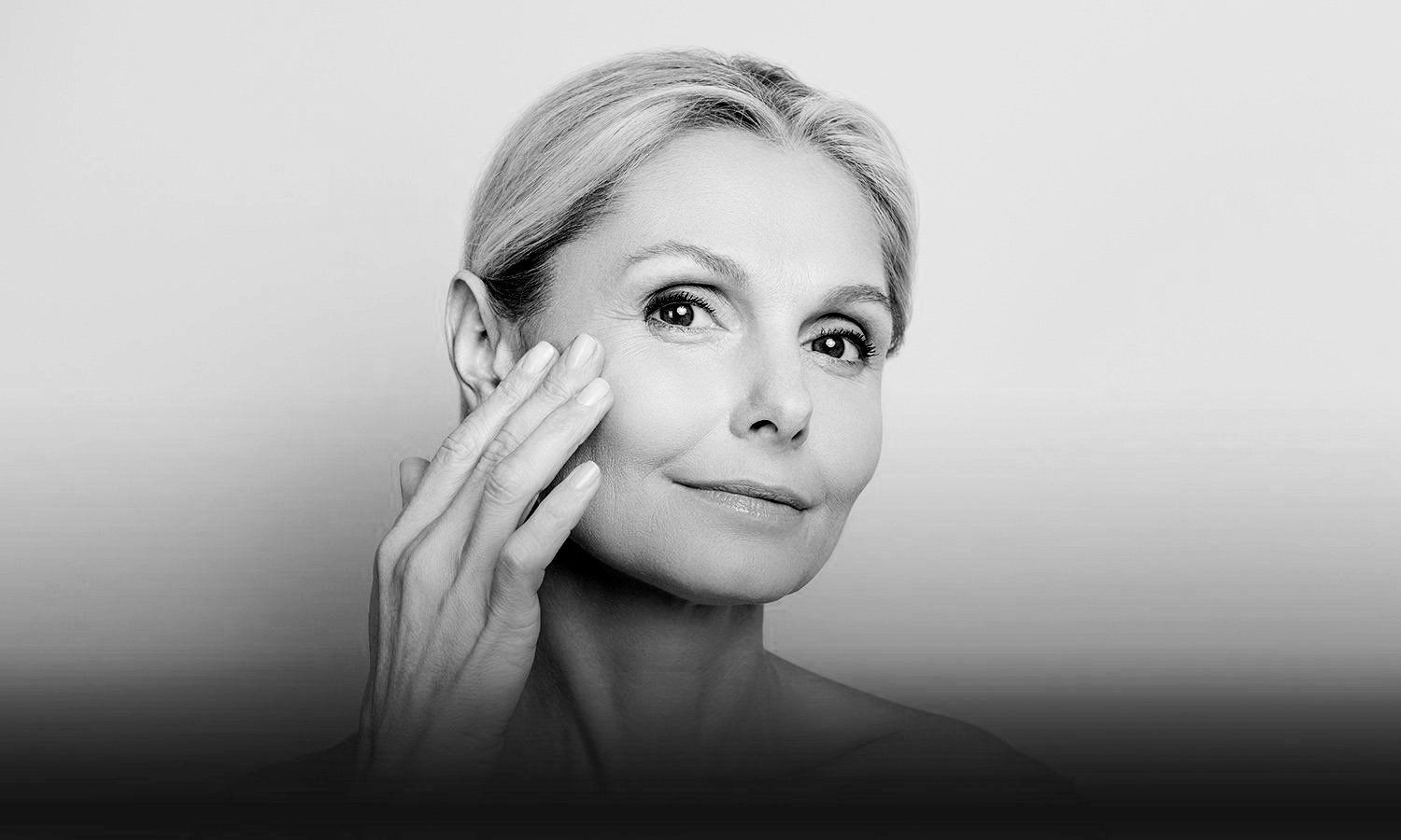 black and white photo of a mature woman touching her face and smiling