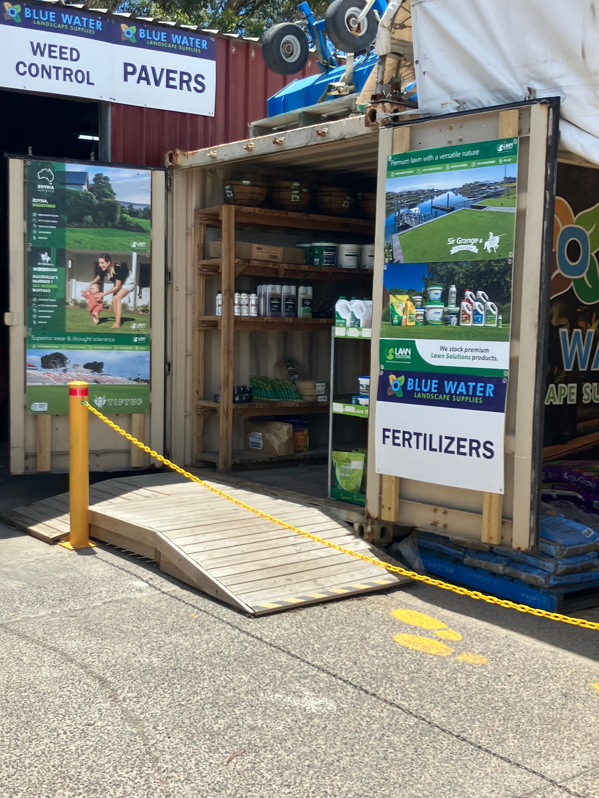 A shop with a ramp made from a shipping container displaying weed control, pavers, and fertilizer products.