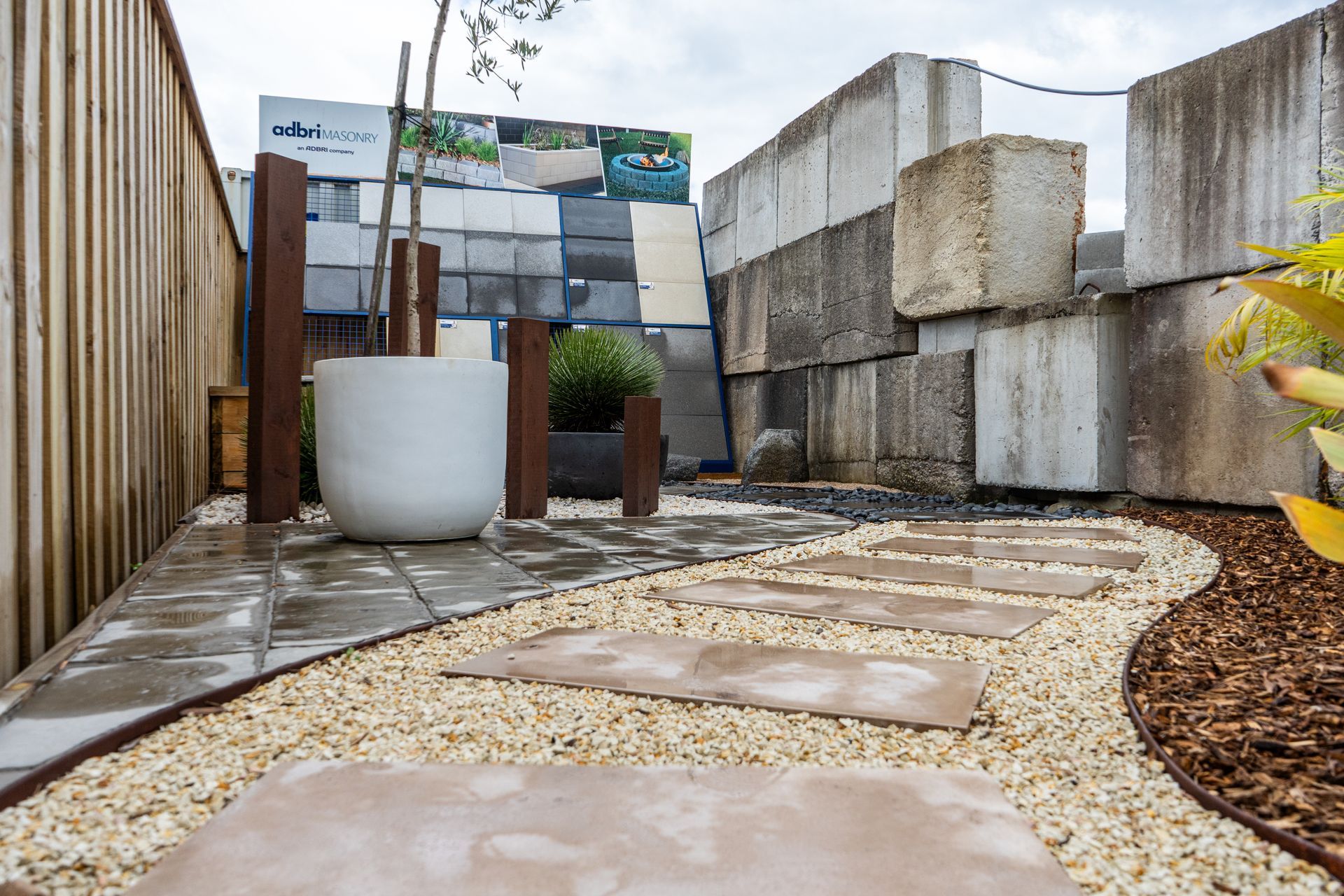 Modern outdoor patio with stone path, gravel, potted plants, and concrete block seating areas