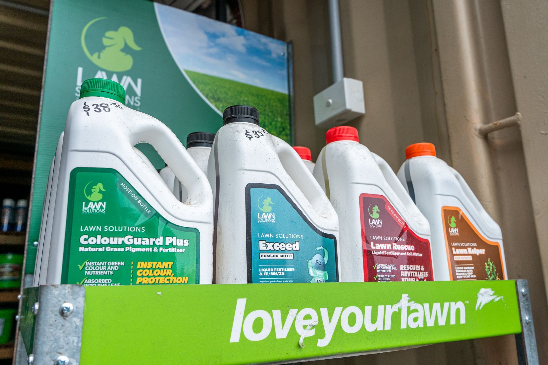 Gardening product bottles on a shelf with a green “love your lawn” sign