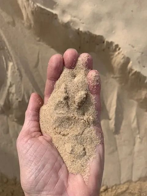Hand Holding a Mound of Tan Sand — Blue Water Landscape Supplies in Salamander Bay, NSW