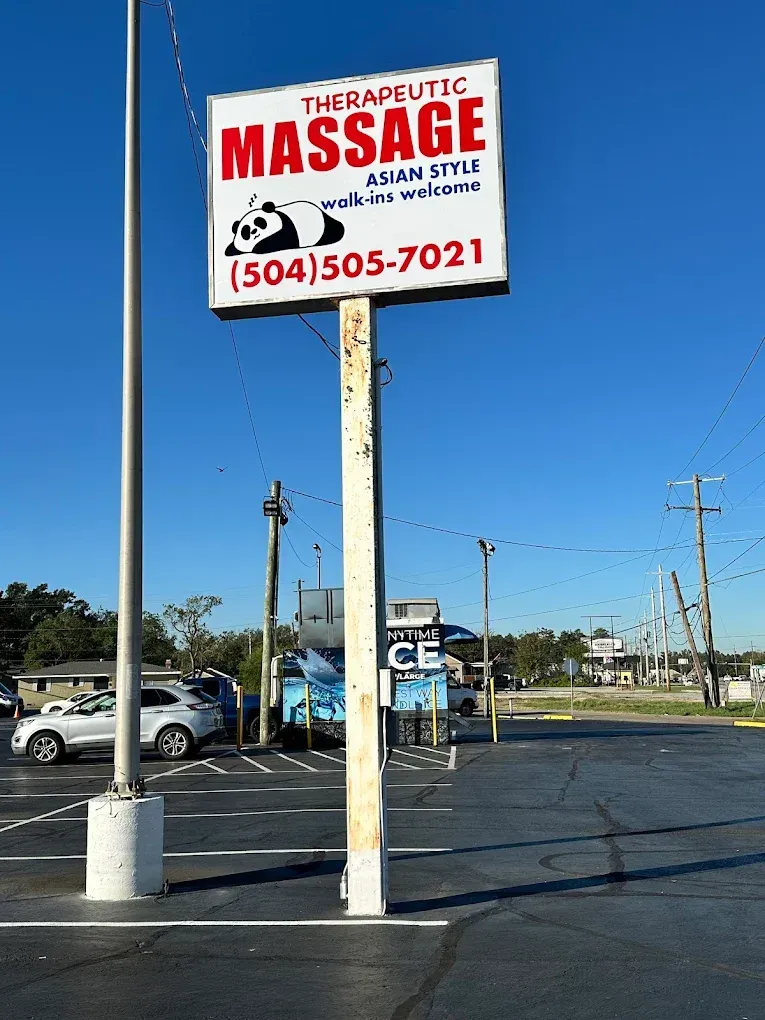 Therapeutic massage sign on a pole in a parking lot under a blue sky