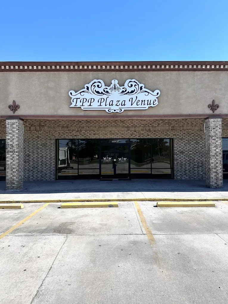 Empty storefront with a decorative sign, brick facade, and glass entrance under a clear blue sky.