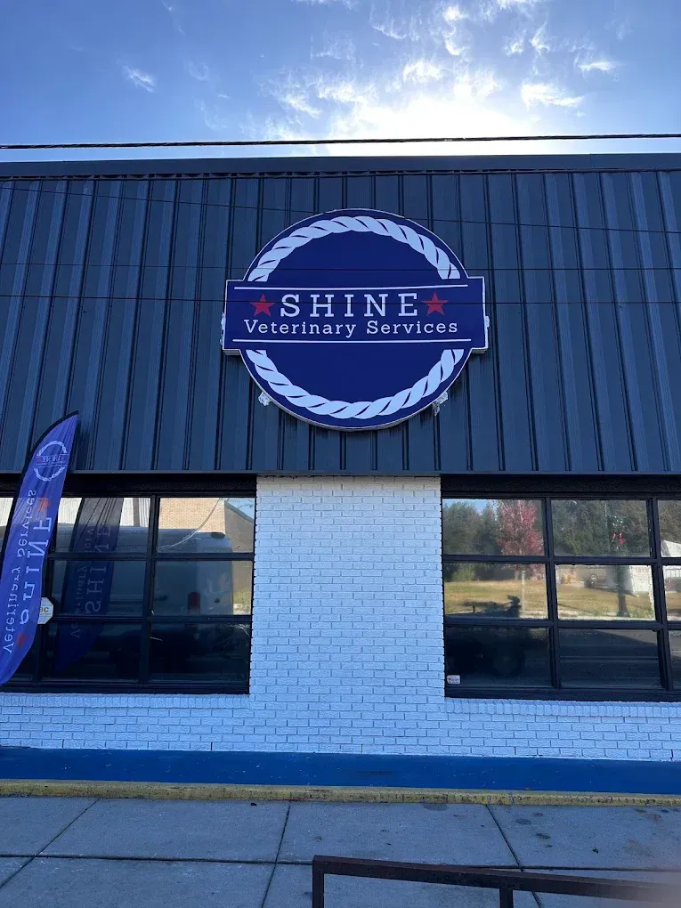 Exterior of SHINLA Veterinary Services building with dark siding, blue trim, and large front windows