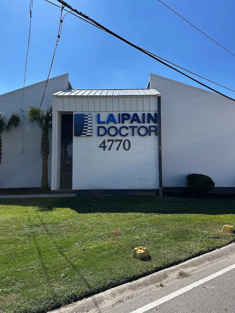 LAPAIN DOCTOR sign on a white building beside a grassy roadside under a blue sky