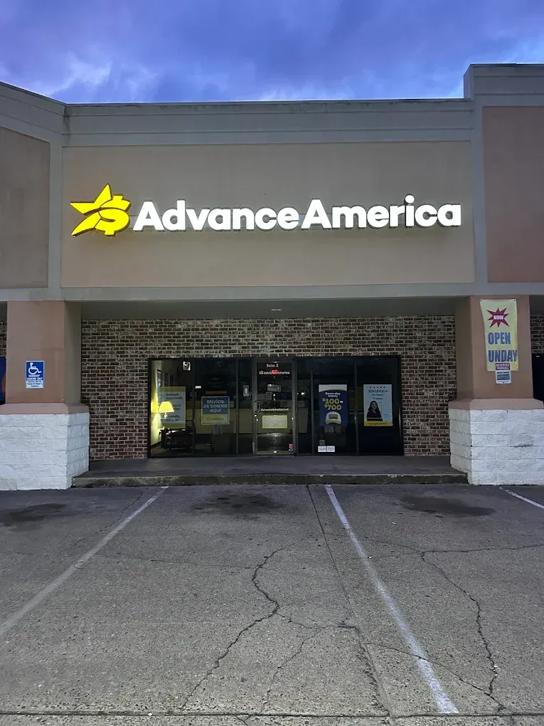 Advance America storefront with yellow logo above glass entrance at dusk