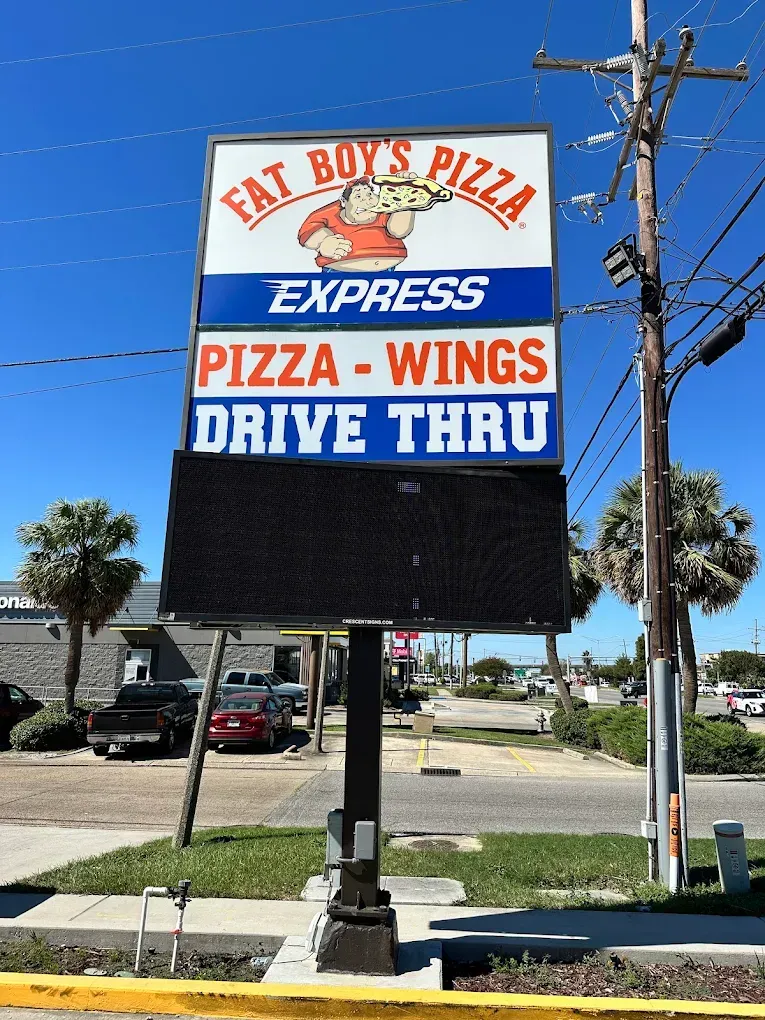 Fat Boy’s Pizza Express sign with “Pizza, Wings, Drive Thru” on a sunny street corner