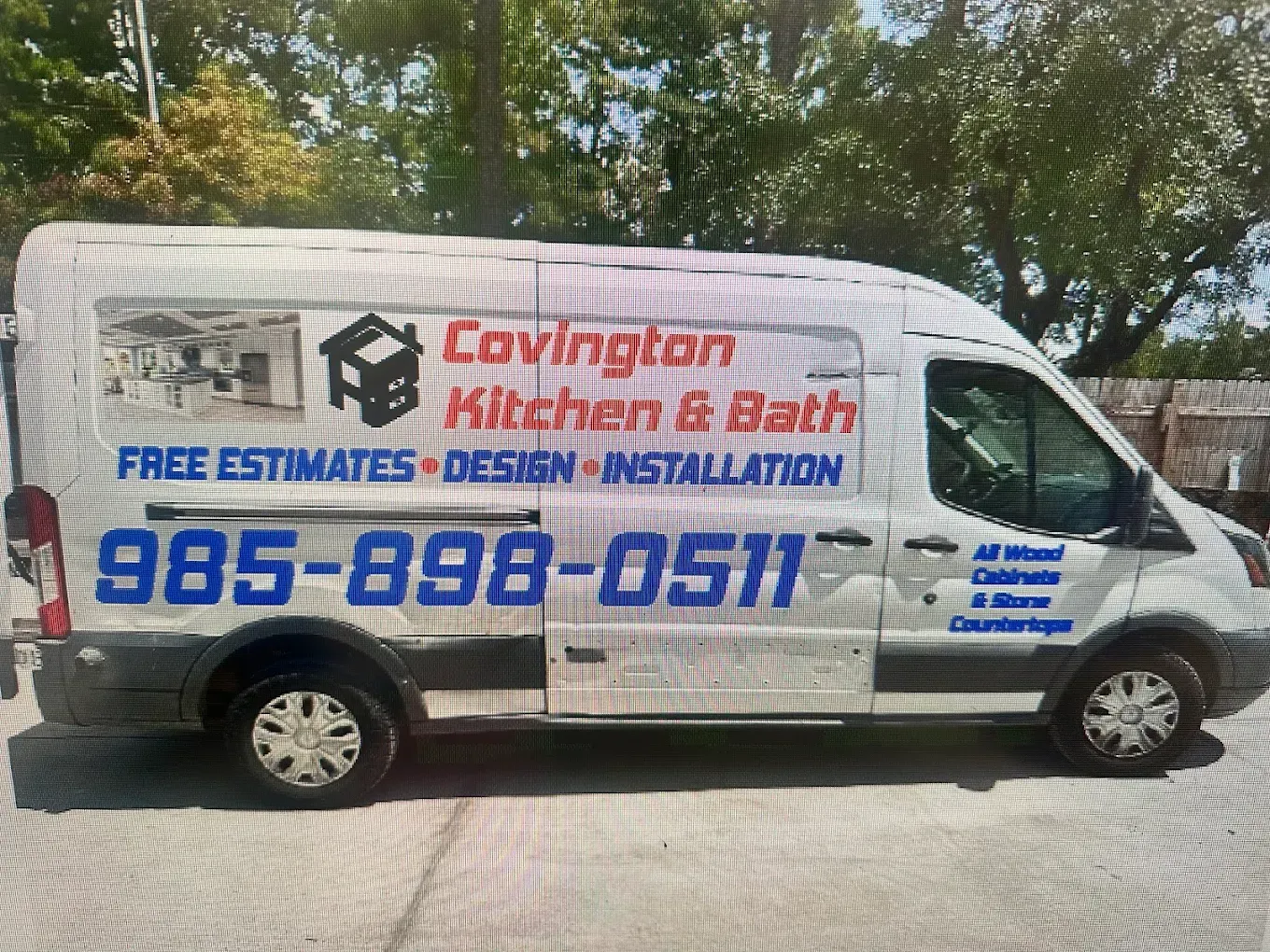 White service van with Cavington Kitchen & Bath logo and phone number parked outdoors under trees
