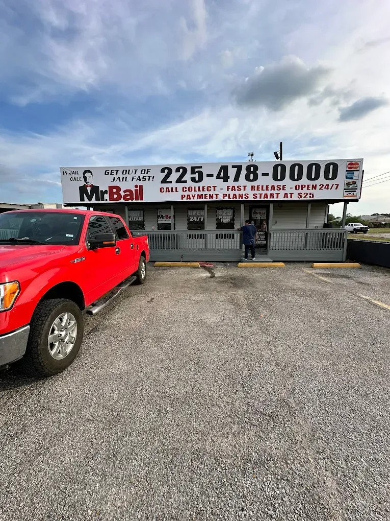 Red pickup in front of Mr. Bull auto repair shop with large phone number sign.