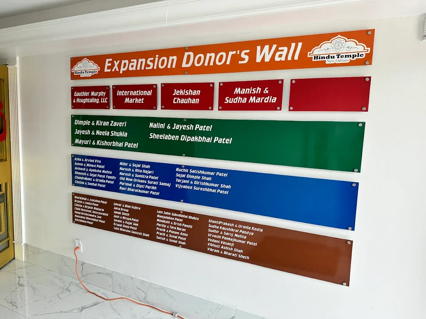 Expansion donor wall with orange header and green, blue, and brown name panels in a hallway