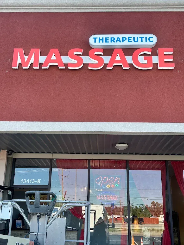Therapeutic massage storefront sign with pink “MASSAGE” letters on a red facade