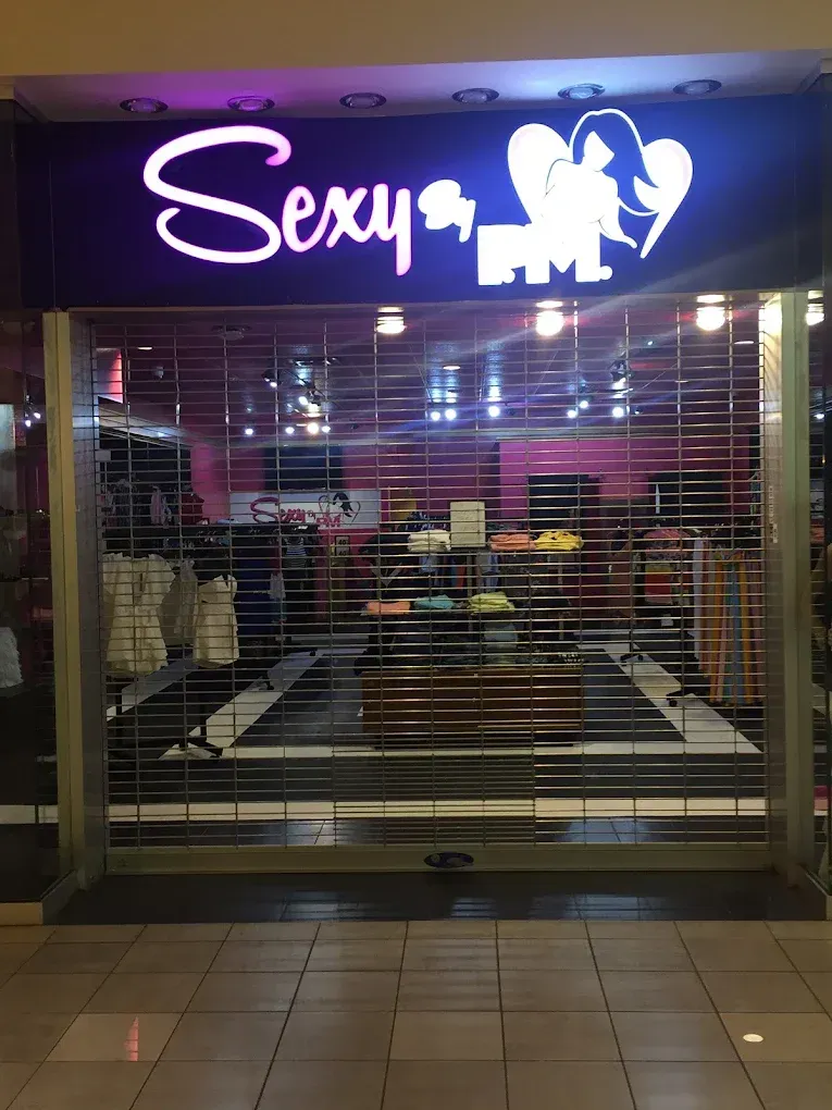 Closed storefront with purple neon “Sexy” sign above a shuttered entrance and tiled walkway