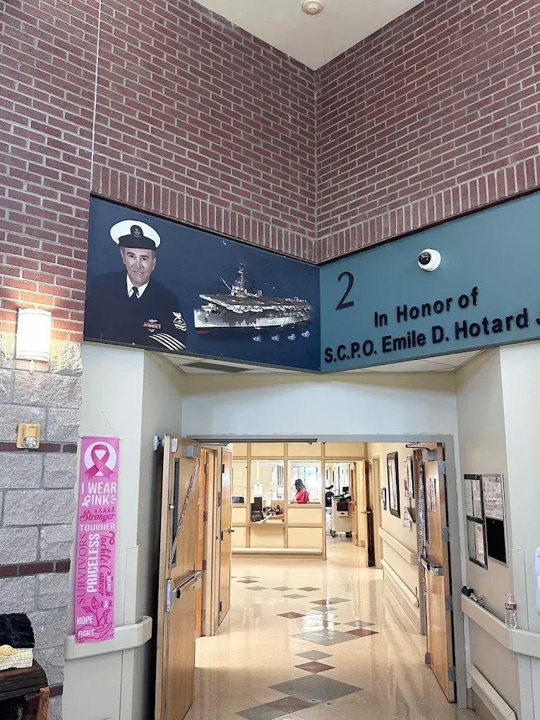 Hospital corridor entrance with memorial sign for S.C.P. Emile D. Hotard and a portrait banner