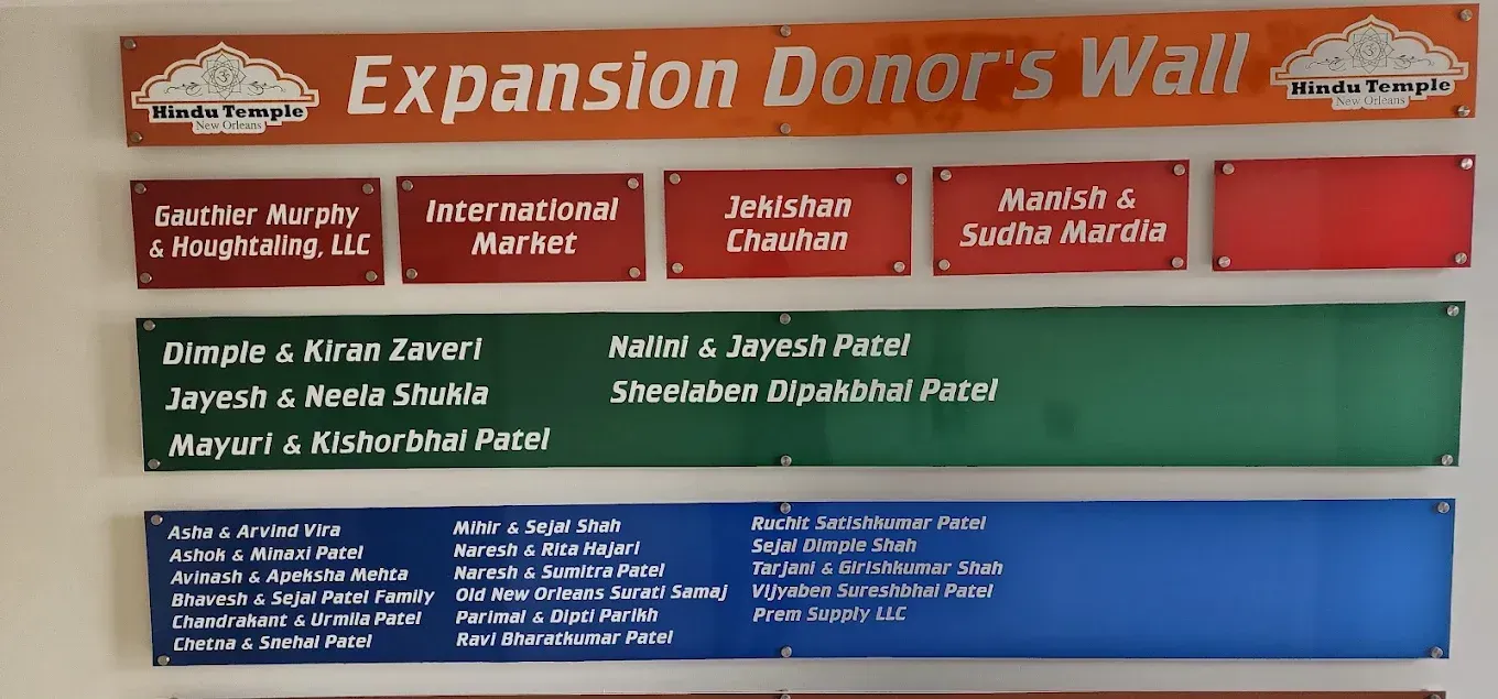 Colorful donation wall sign with red, green, and blue name plaques on a white board