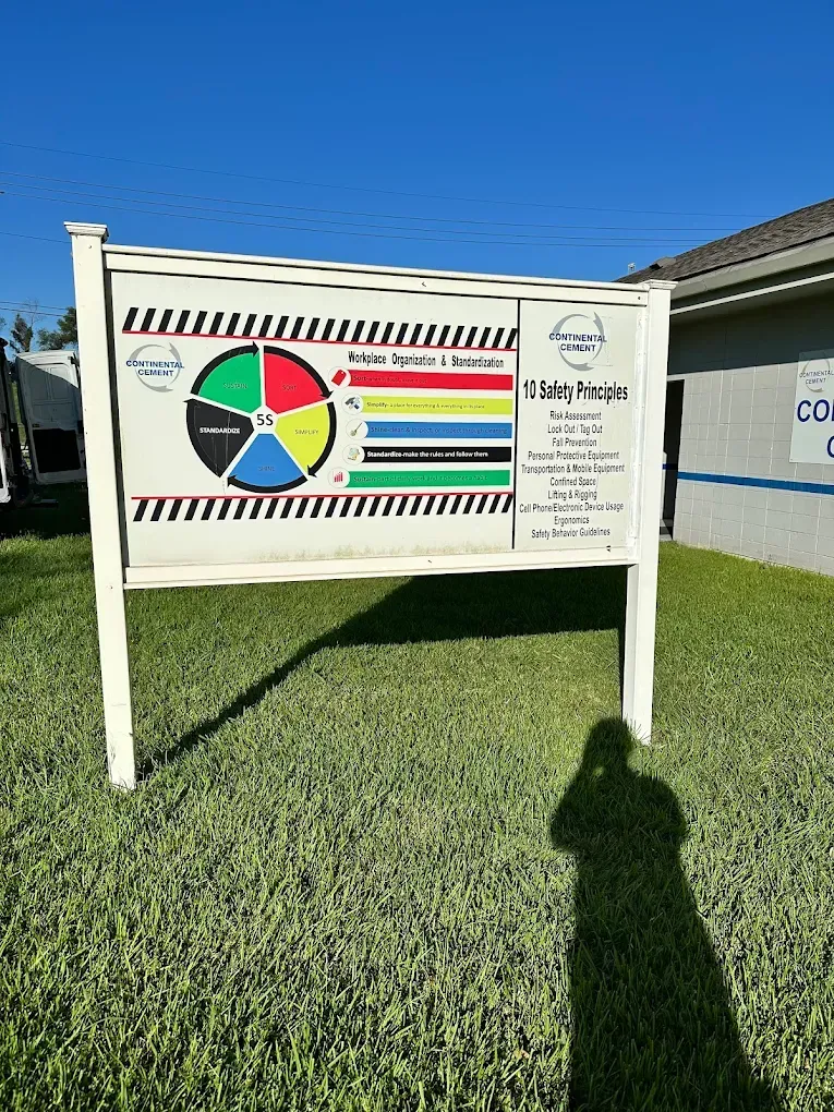 Outdoor sign with colorful chart and text board on a grassy lawn under a blue sky.