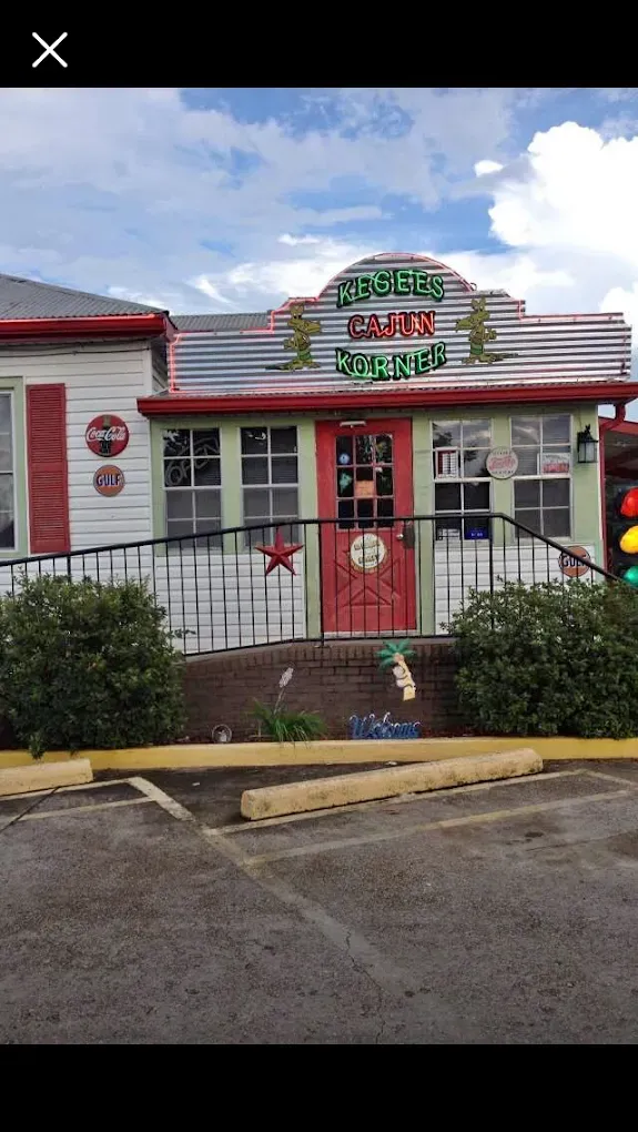 Front view of a red-and-white diner with a green sign and striped roof, seen from the parking lot