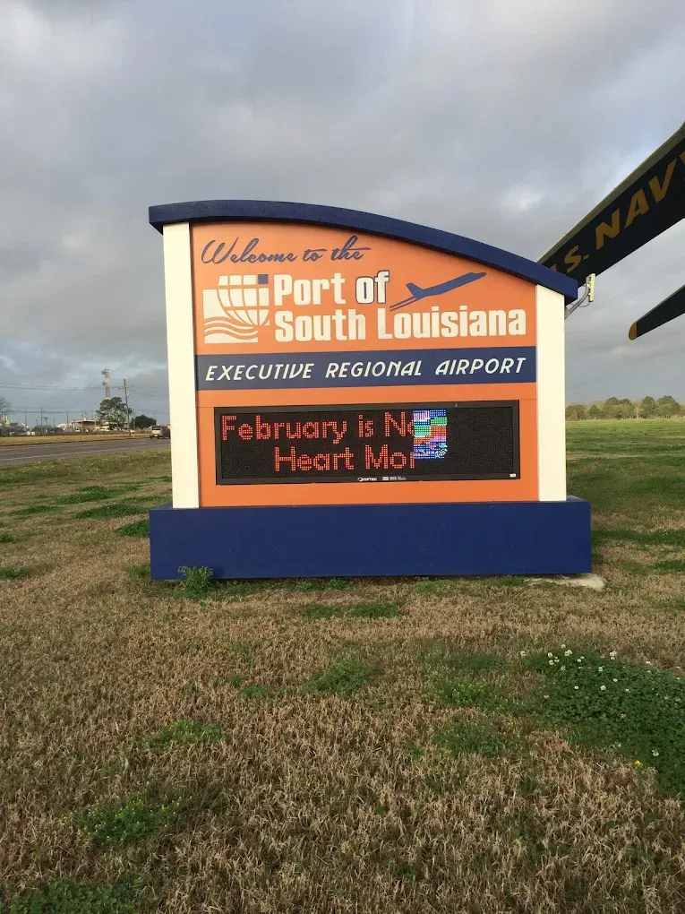 Port of South Louisiana Executive Regional Airport sign on a grassy roadside under a cloudy sky