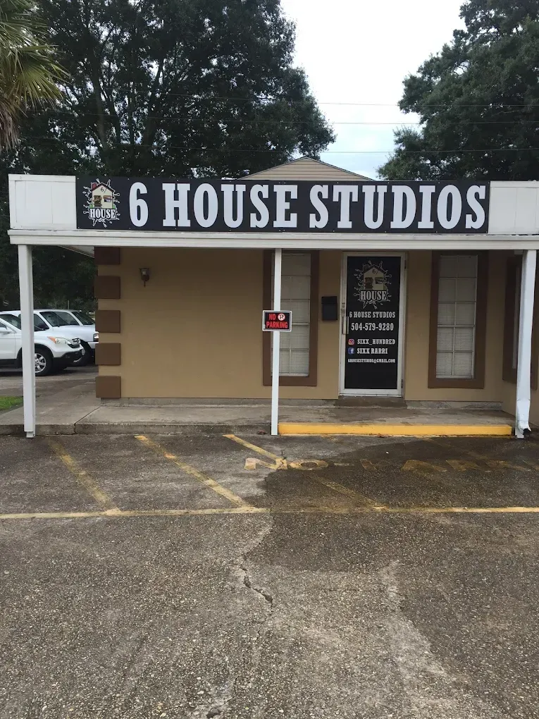 Storefront with sign reading “6 House Studios” and a small parking lot in front