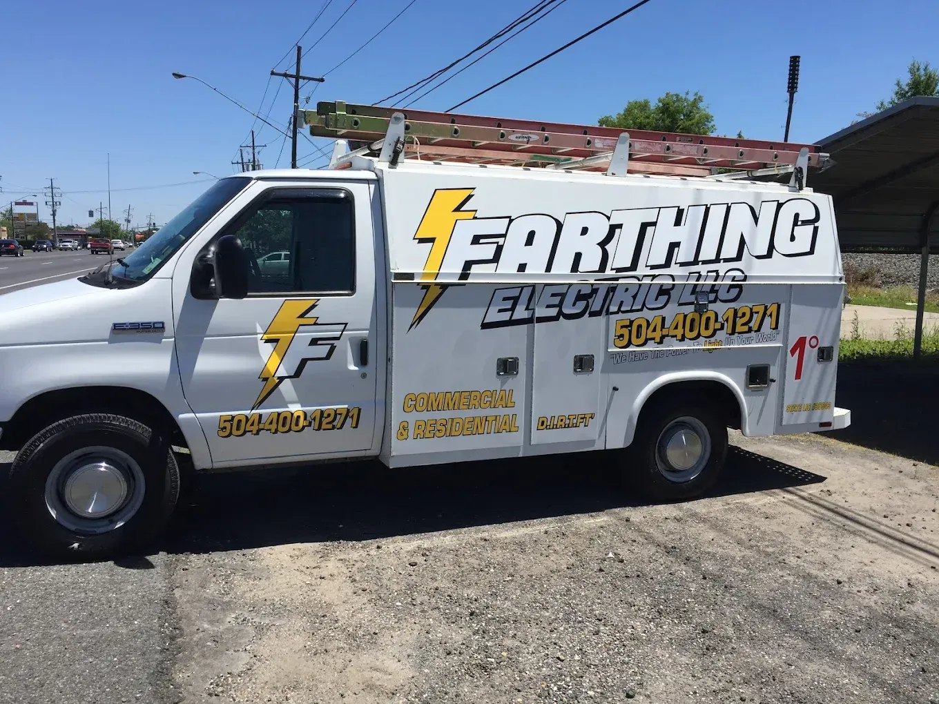 White utility truck with “Earthing Electrical” signage parked outdoors on a sunny street.