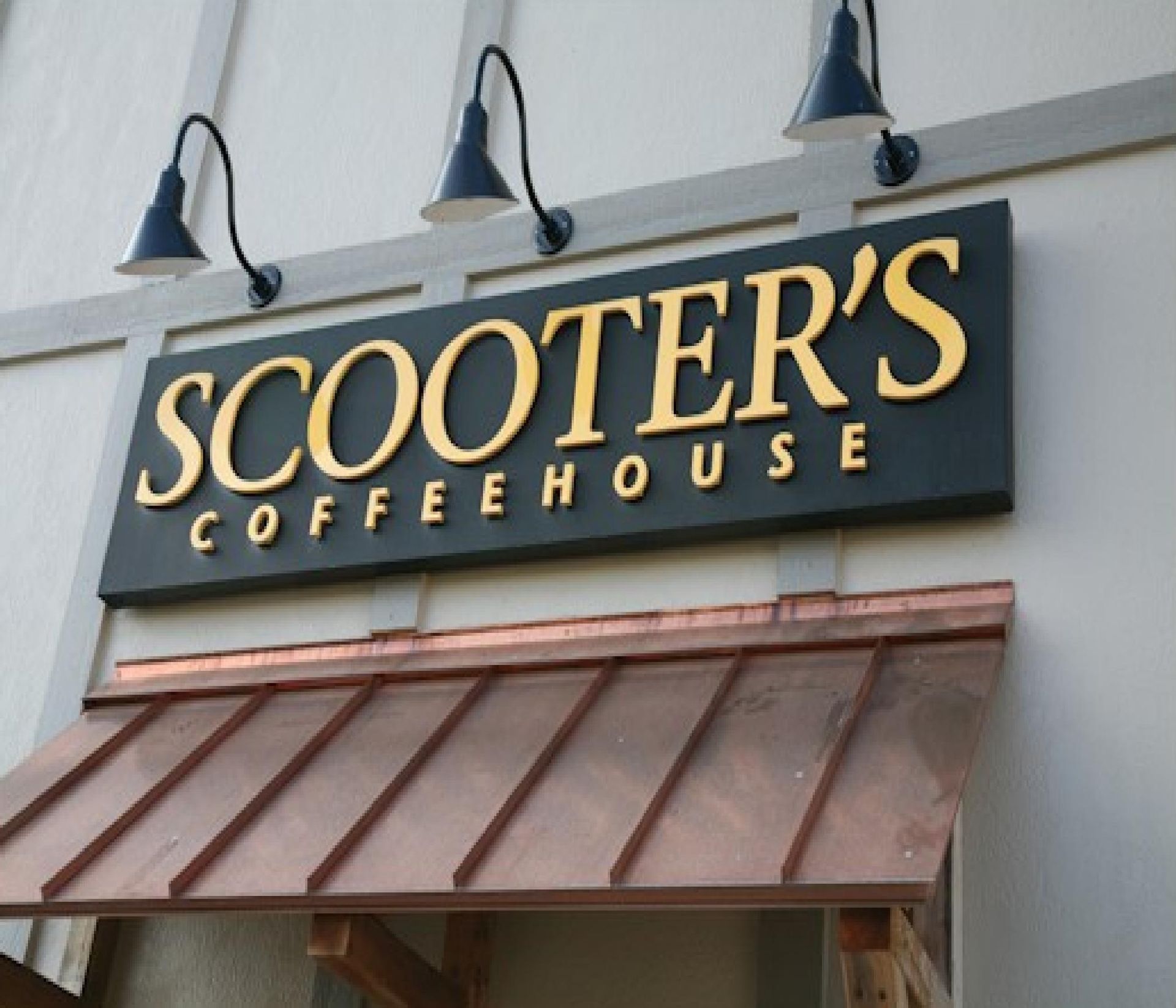 Scooter’s Coffeehouse storefront sign on a building with wall-mounted lights and a copper awning