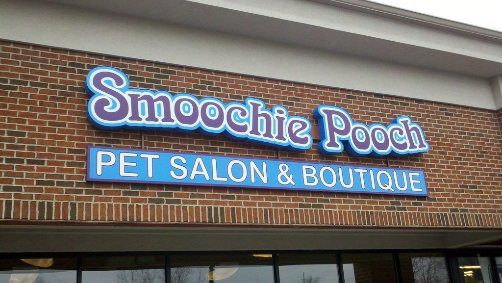 Storefront sign reading “Smoochie Pooch Pet Salon & Boutique” on a brick building.