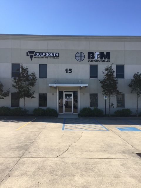 Office building entrance with Gulf South and BFM signs, number 15, and a parking lot in front