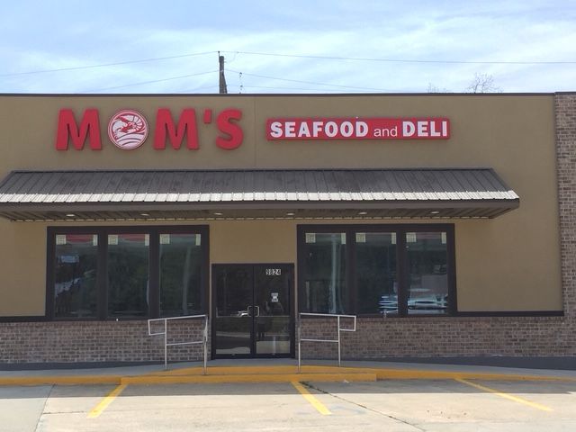 MOM’s Seafood and Deli storefront with beige facade, red sign, and dark awning in a strip mall parking lot
